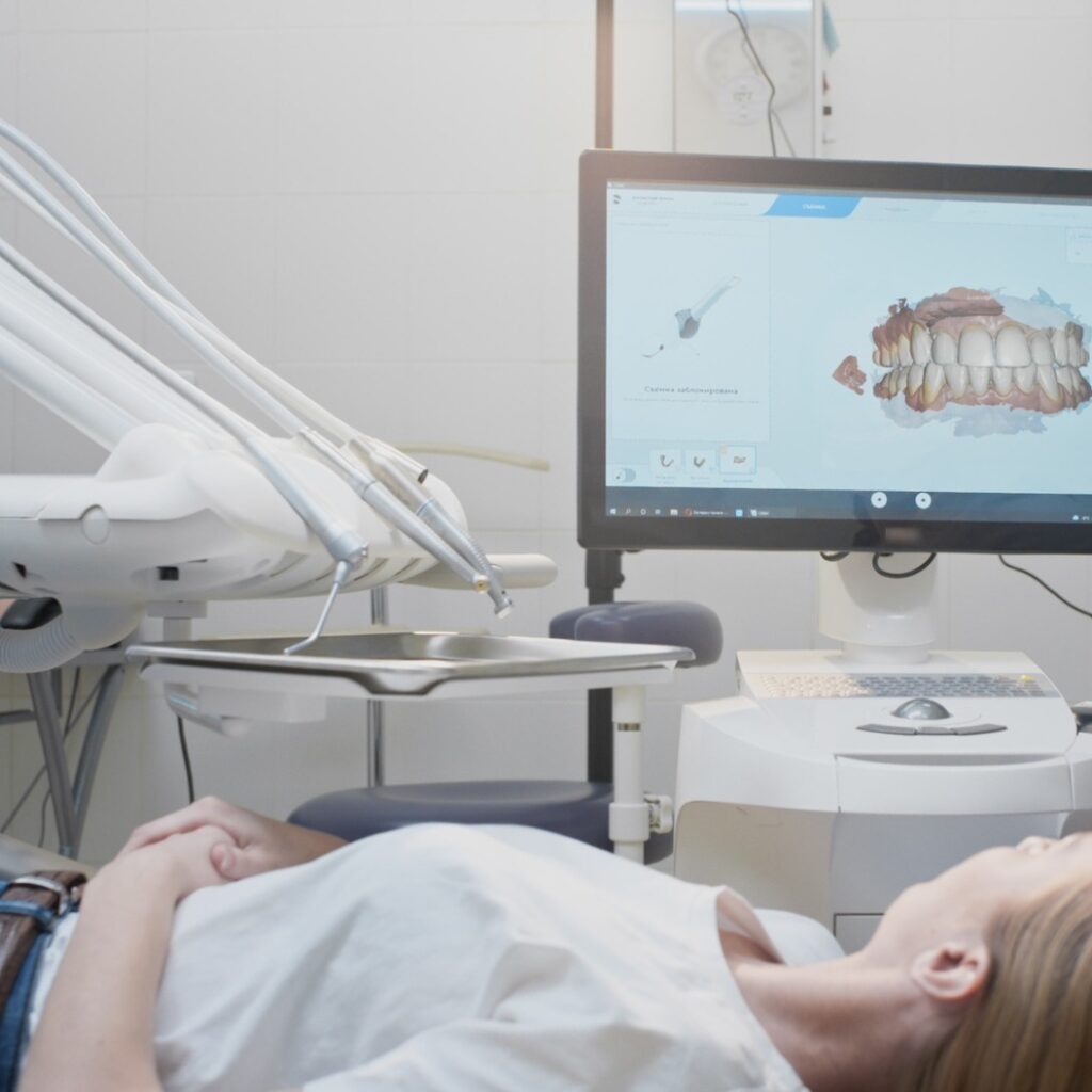 Girl doctor dentist demonstrates a 3D model of teeth on a touch monitor. Dental consultation in the clinic, diagnostics